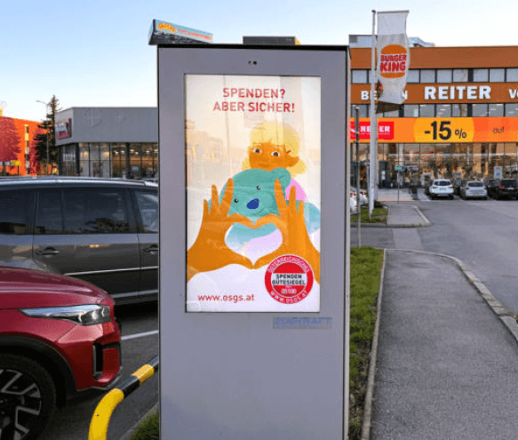 Auf dem Bild sieht man einen Screen, der den OSGS Spot zeigt. Der Spot zeigt ein animiertes Video mit einem Kind und einem Kuscheltier. Mit dem OSGS Logo.